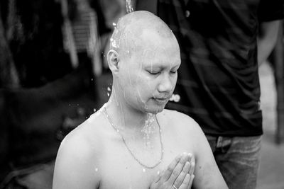 Close-up of bald man with eyes closed and hands clasped