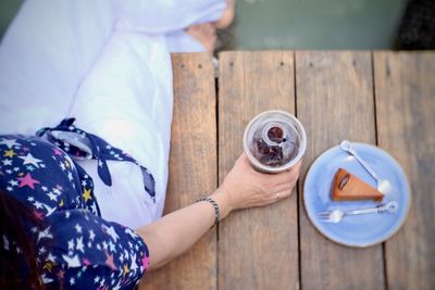 High angle view of woman holding coffee cup on table