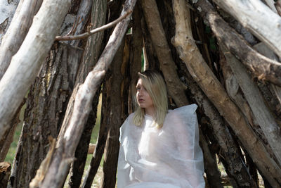 Woman standing by tree trunk in forest