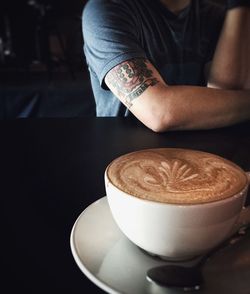 Midsection of man sitting with coffee at cafe