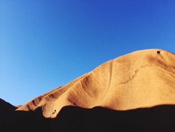 Low angle view of desert against clear blue sky