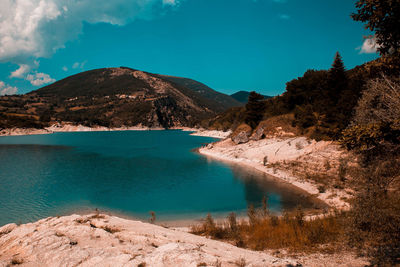 Scenic view of lake by mountains against sky