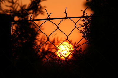 Silhouette fence against sky during sunset