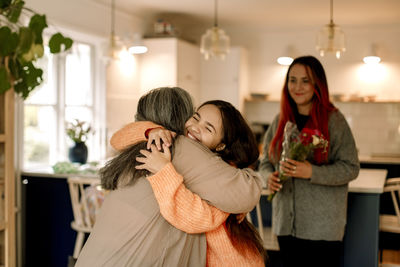 Happy girl embracing grandmother and greeting at home