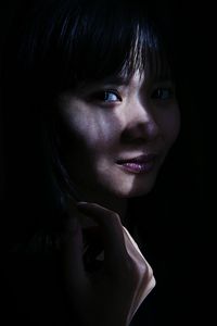 Portrait of young woman smiling against black background