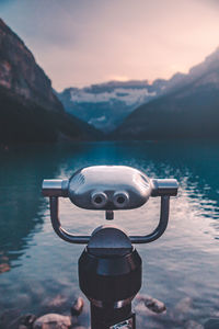 Camera on mountain by lake against sky during sunset