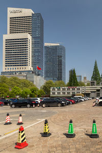 People on road by buildings against sky in city