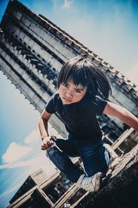 Portrait of boy with umbrella against sky