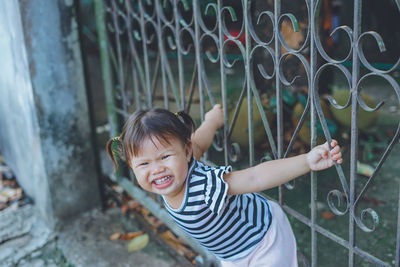 Portrait of cute girl playing on gate