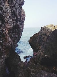 Rock formations by sea against clear sky