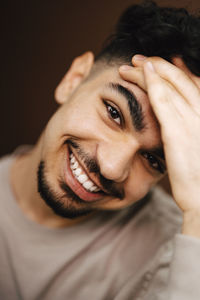 Portrait of smiling man with head in hand at studio