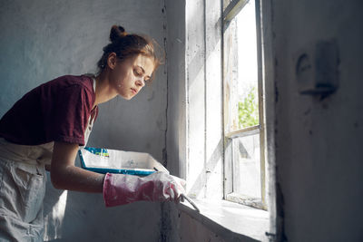 Side view of woman looking at window
