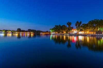 Scenic view of lake against clear blue sky at night