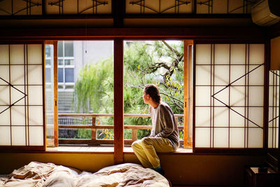 Woman sitting on window sill at home