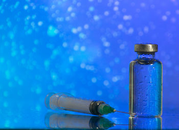 Close-up of glass bottle on table against blue background