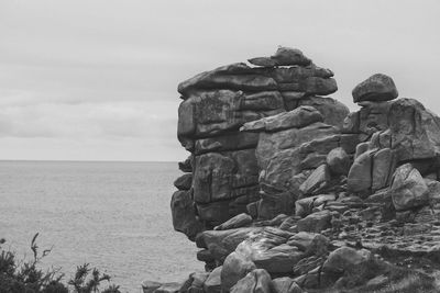 Stack of rocks by sea against sky