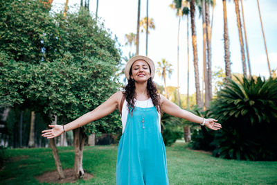 Portrait of smiling young woman standing against trees