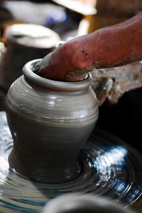 Midsection of man working on pottery wheel