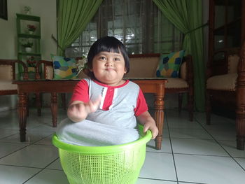 Portrait of cute girl sitting on chair at home