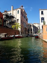 Canal in city against clear sky