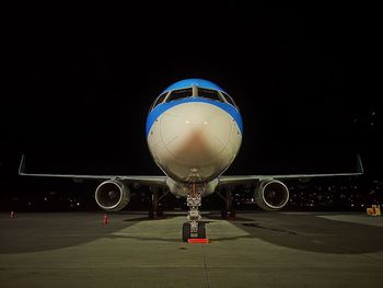 Airplane on airport runway against clear sky at night