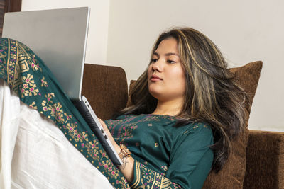 Portrait of young woman sitting on sofa at home