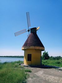 Traditional windmill on field against clear blue sky