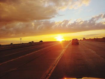Cars on road against sky during sunset