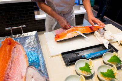 Midsection of man preparing fish on table