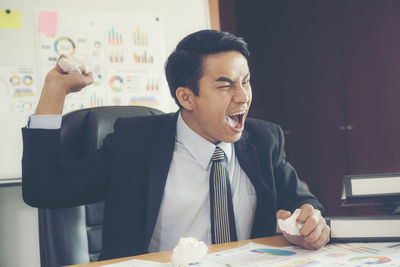 Frustrated businessman screaming while sitting in office