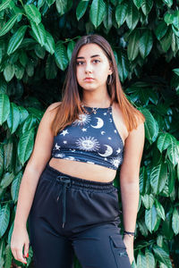 Portrait of a beautiful young woman standing against plants