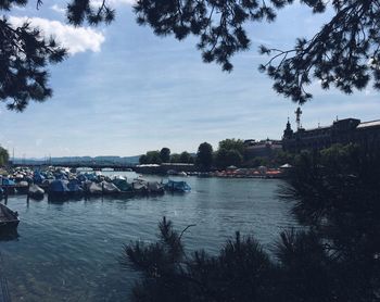 Boats moored on river in city against sky
