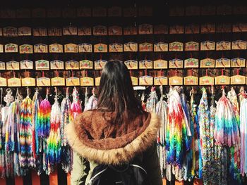 Rear view of woman in fur coat standing against market stall