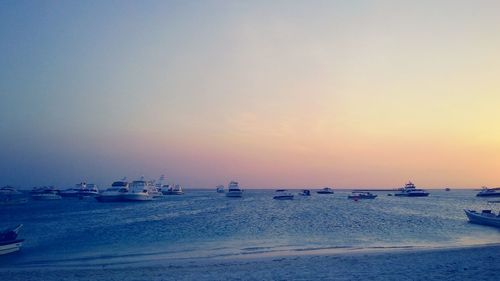 Boats in sea at sunset