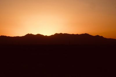 Scenic view of silhouette mountains against orange sky