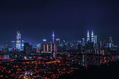 Illuminated buildings in city against sky at night