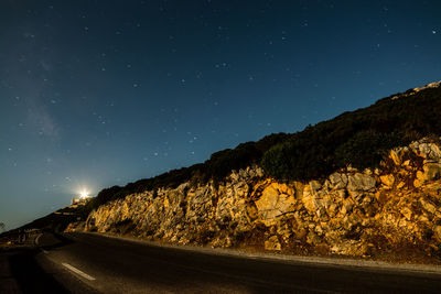 Road amidst illuminated mountains against sky at night