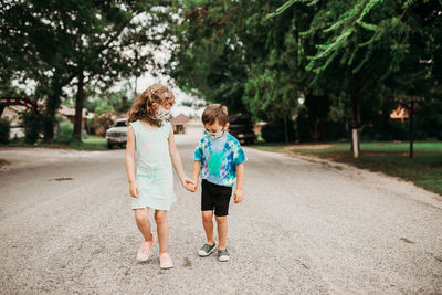 Two young kids going for walk together wearing homemade masks