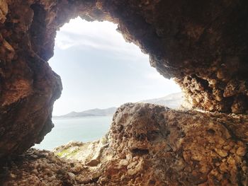 Rock formation by sea against sky