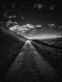 Road amidst field against sky