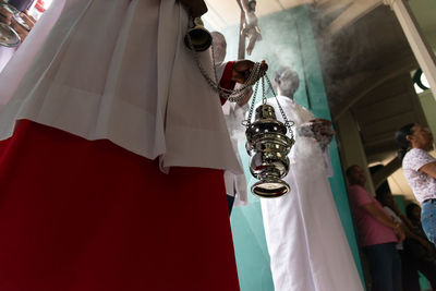 Lower part of catholic church members with incense in the campo santo 