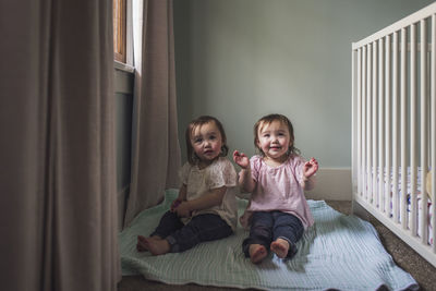 Portrait of twin toddler girls smiling in window light