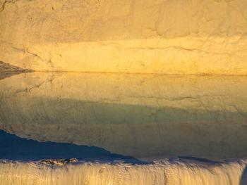 Rock formation reflecting on travertine pool at pamukkale