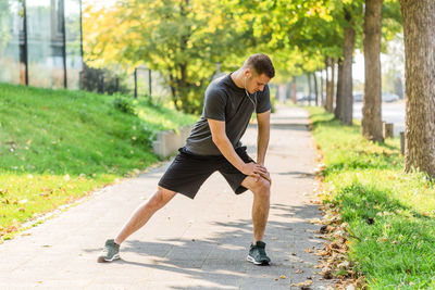 Side view of young man sitting on footpath