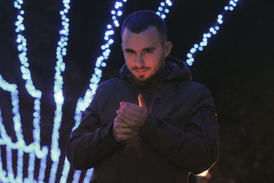 Young man standing against illuminated light painting