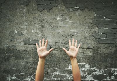 Close-up of hands against weathered wall