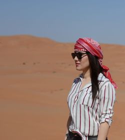 Beautiful woman standing in desert against sky