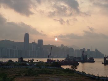 Scenic view of sea by buildings against sky during sunset