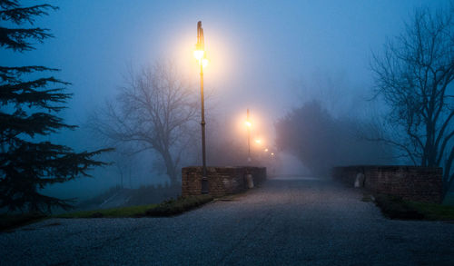 Illuminated street light against sky at night