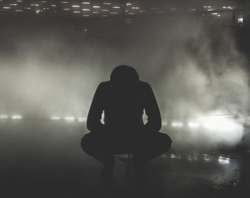 Man crouching against sky at night